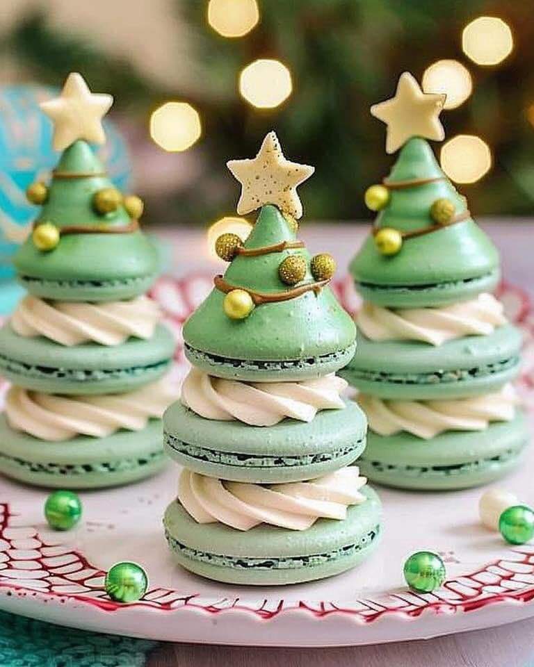 Green macarons stacked as Christmas trees with gold stars and pearl decorations on pink and white striped surface