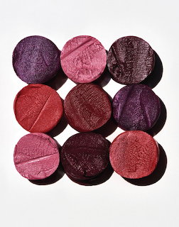 Grid of nine round makeup eyeshadow pans in berry, plum, and pink tones