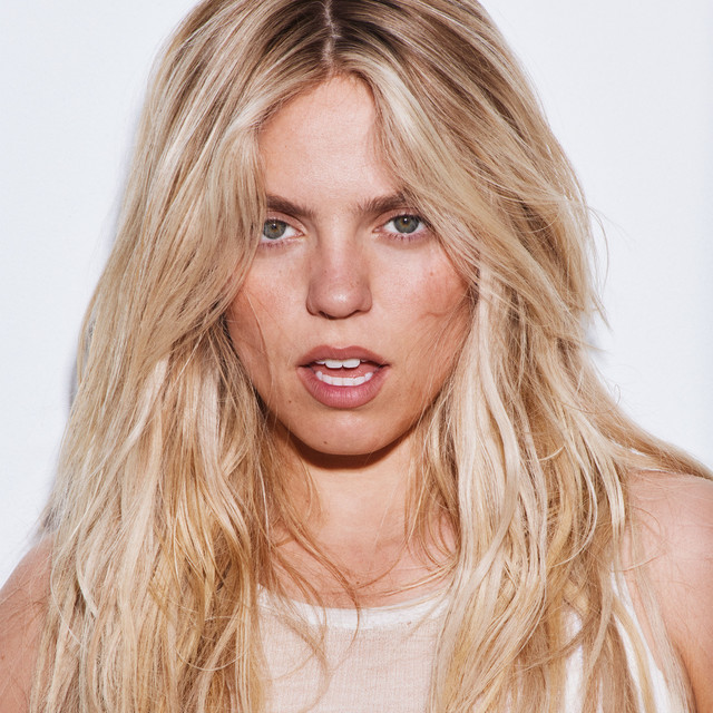 Portrait of blonde woman with long wavy hair looking at camera