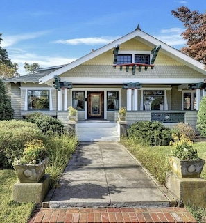 Front view of a craftsman-style house with porch, walkway, and garden shrubs