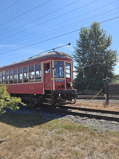 Red and cream vintage BCER 1225 streetcar on railway tracks with trees and blue sky