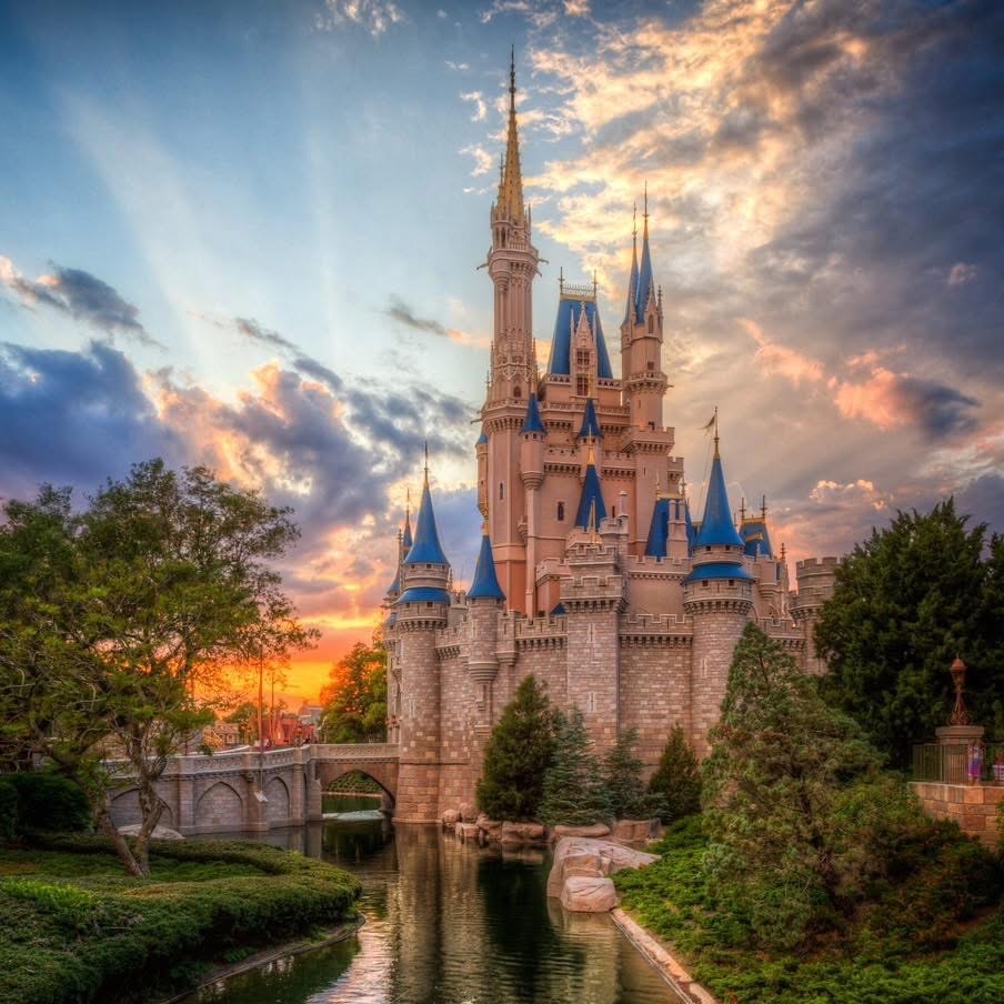 Cinderella Castle at sunset with dramatic orange and blue sky reflected in moat