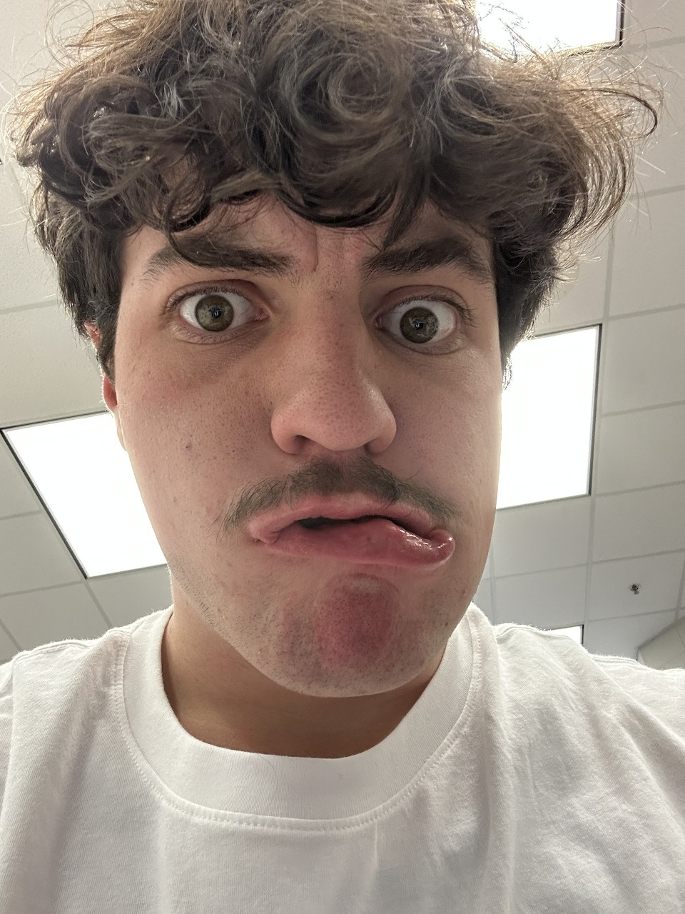 Young man making a funny face with wide eyes and pursed lips in an indoor selfie