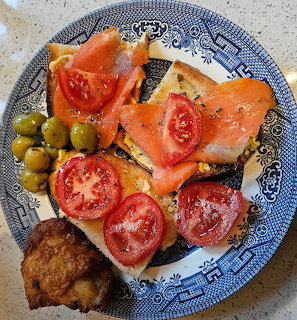 Open-faced sandwiches with salmon and tomato on decorative blue plate with olives and fried chicken