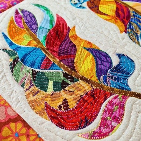 Colorful quilted bird with rainbow feathers on white textured fabric background