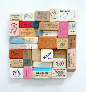 Grid of vintage rectangular erasers in various colors with printed text and numbers