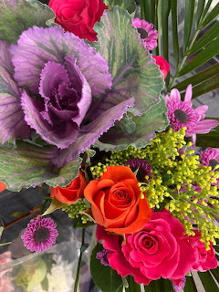 Colorful flower bouquet with purple cabbage, pink and orange roses, and small yellow blooms