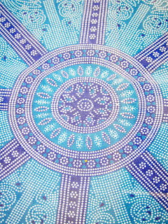 Circular mandala with blue and purple mosaic pattern radiating from center with geometric dotted designs