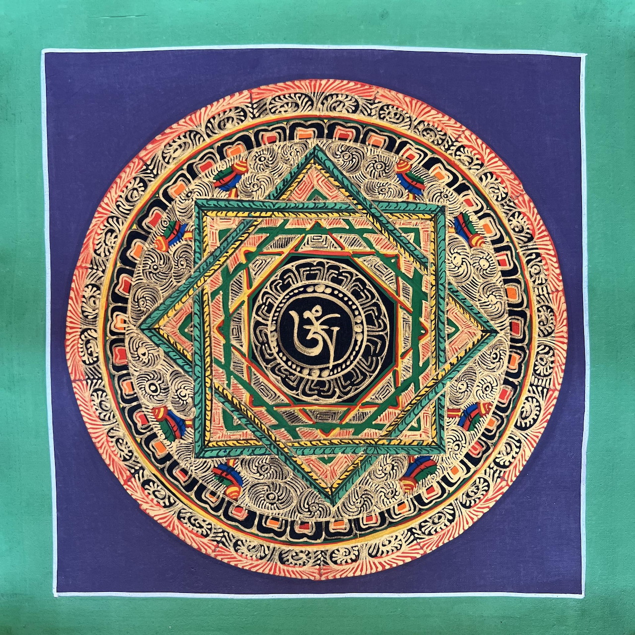 Circular mandala painting with Om symbol center, geometric patterns, teal and coral tones on blue background
