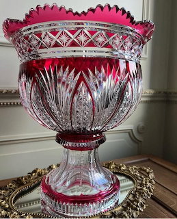 Ornate red and clear cut crystal vase with detailed geometric patterns on a mirrored tray