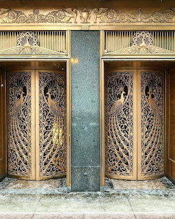 Ornate bronze peacock doors with intricate Art Deco metalwork and feather designs on a Chicago building entrance