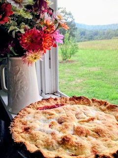 Homemade pie on windowsill with flower bouquet and countryside view