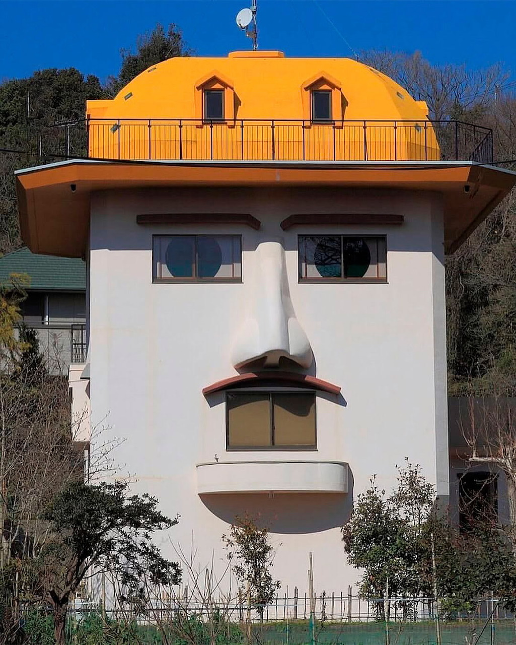 Quirky house with face-like facade featuring dome roof, window eyes, and balcony nose