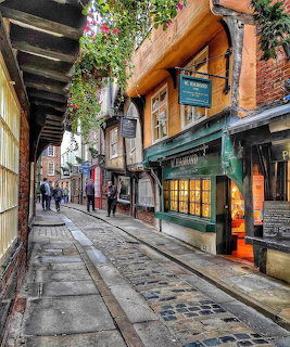 Narrow medieval cobblestone street with timber-framed buildings and shops in York, England