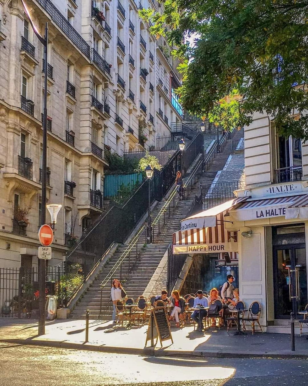 Steep outdoor staircase in Montmartre Paris with cafe seating and apartment buildings