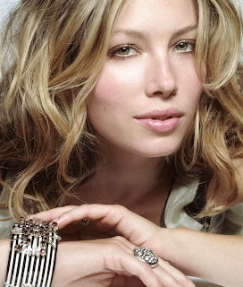 Close-up portrait of a blonde woman with wavy hair wearing a crystal bracelet and ring