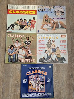 Five vintage compilation album covers arranged on a wooden floor