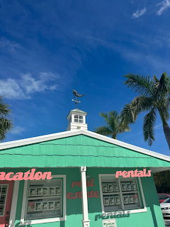 Turquoise vacation rentals storefront with palm trees and blue sky