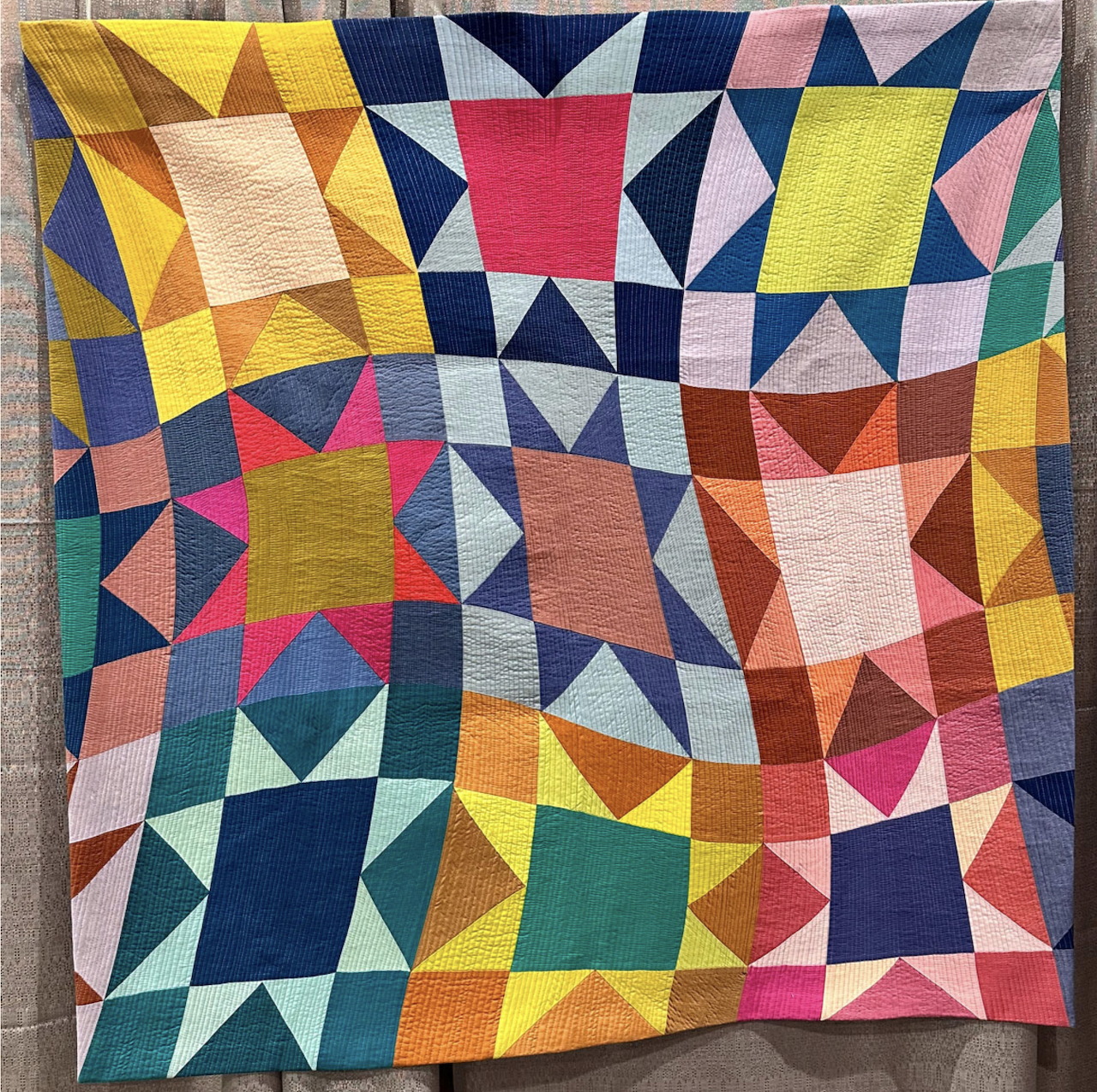 Colorful patchwork quilt with geometric star and triangle blocks in vibrant reds, yellows, blues, and greens