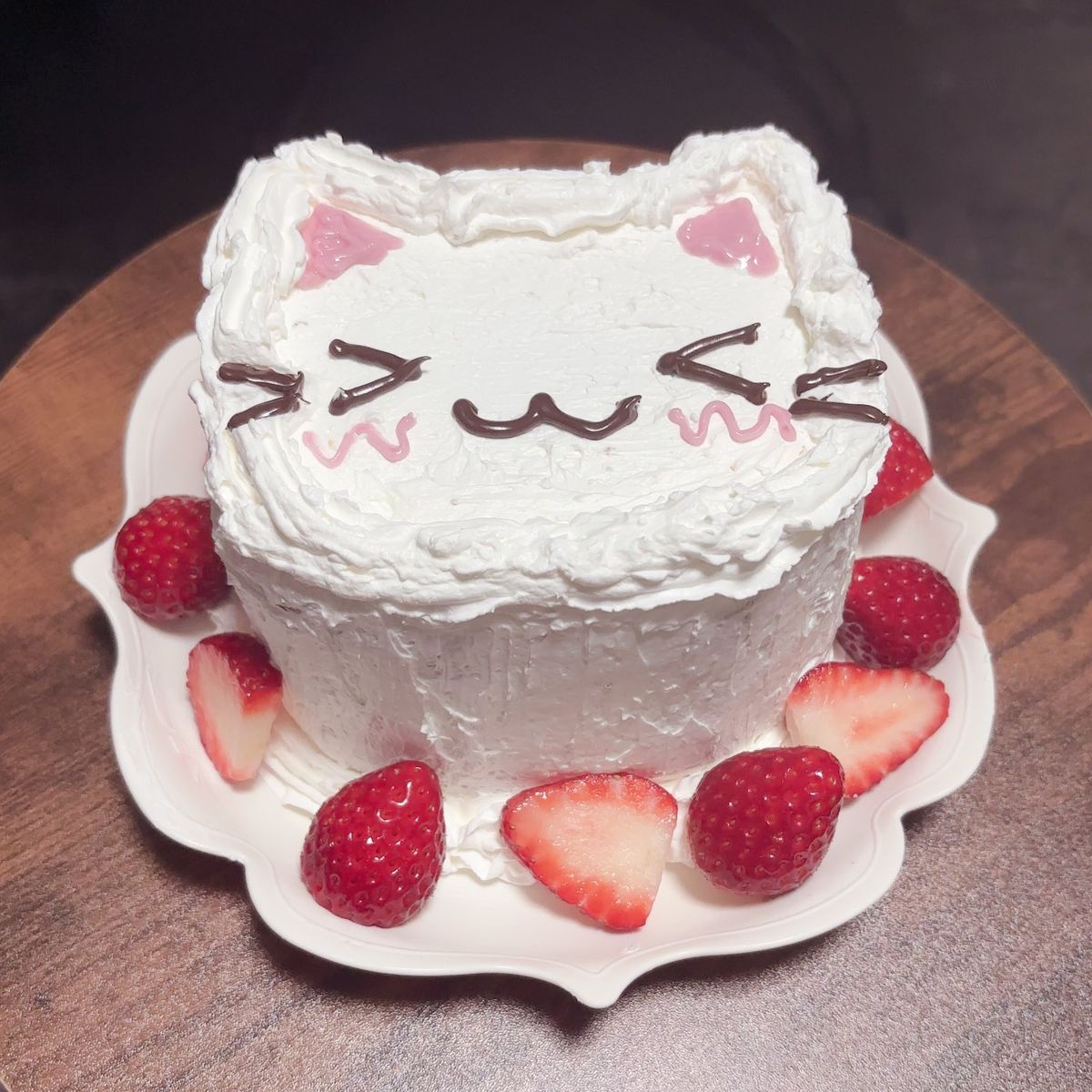 White cat face cake with strawberries on a white plate