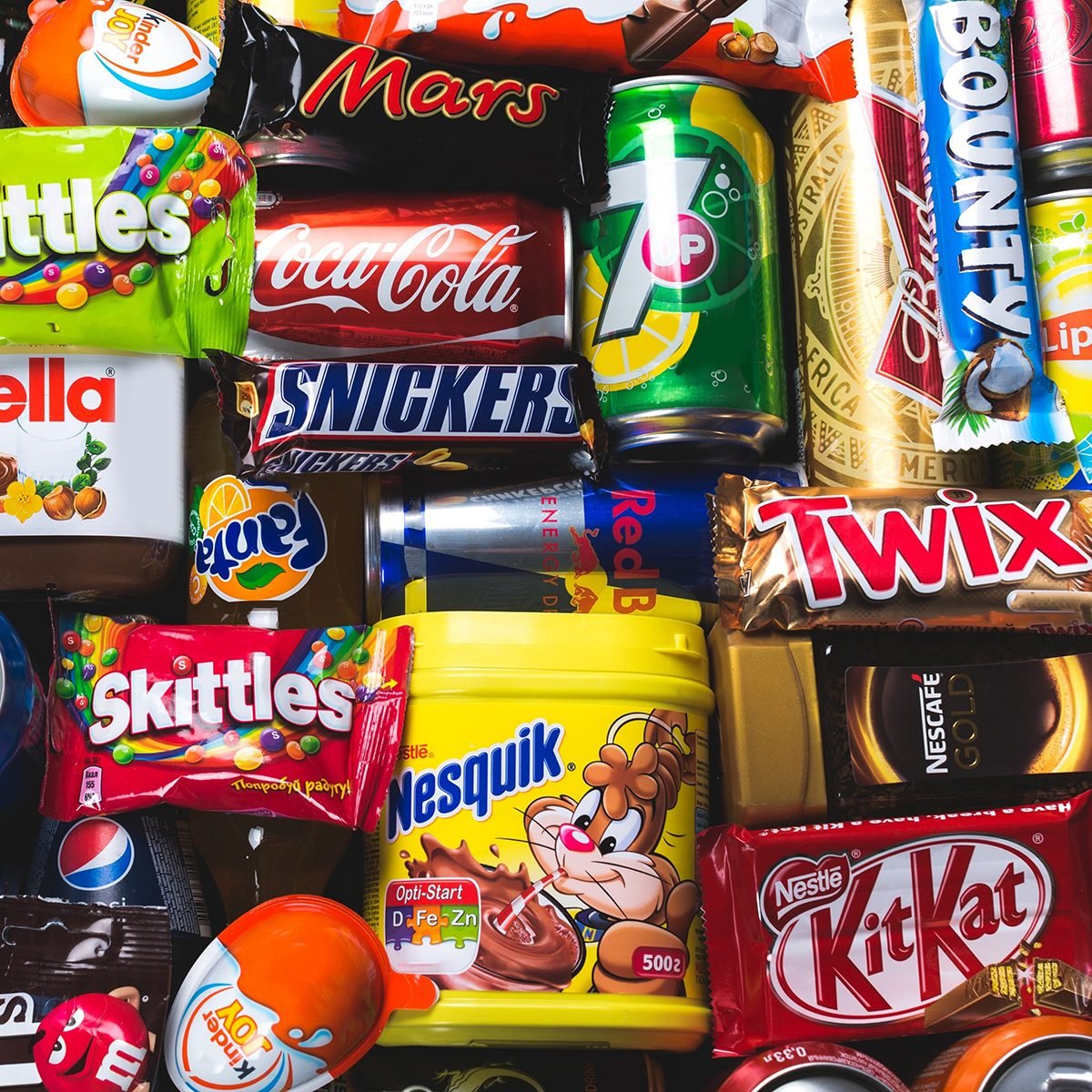 Assorted candy bars, chocolate snacks, soda cans, and sweet treats arranged in a colorful collage