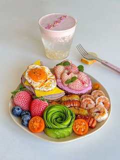 Colorful breakfast plate with avocado rose, eggs, berries, shrimp and pink smoothie