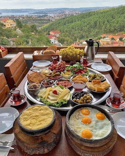Turkish breakfast spread on outdoor terrace table with hillside view