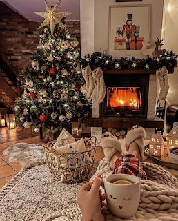 Christmas tree and fireplace in cozy living room with person holding mug