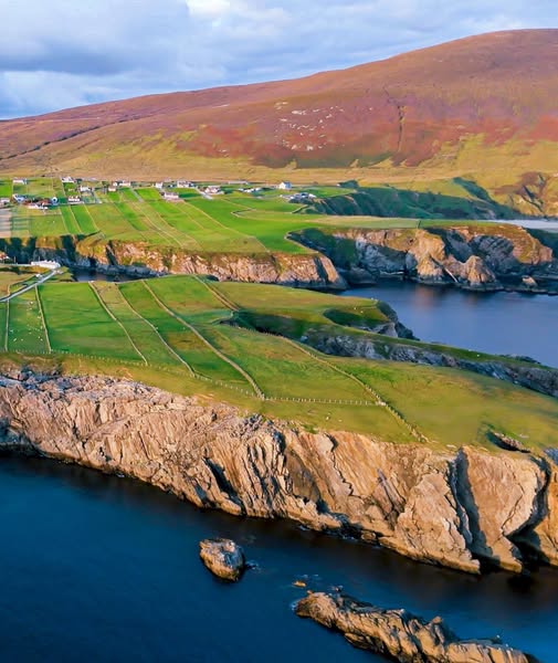 Aerial view of Malin Beg cliffs and green fields along the Irish coastline with dark blue sea