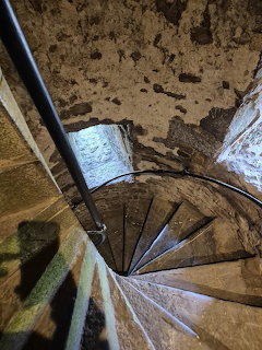 Aerial view of a worn stone spiral staircase descending in a medieval castle tower