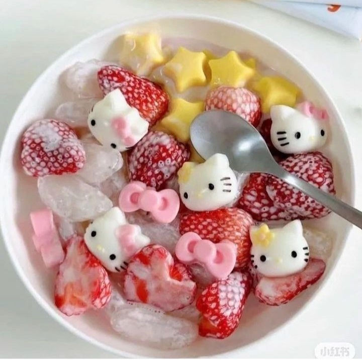 Bowl of kawaii desserts with character faces, stars, strawberries and colorful jellies in pink liquid