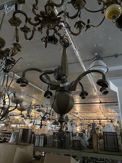 Large chandeliers hanging from ceiling inside a lamp shop showroom with many light fixtures on display