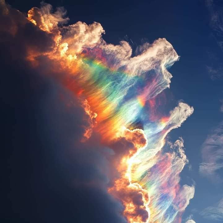 Iridescent rainbow cloud glowing against a dark blue sky