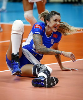 Female volleyball player in blue uniform diving on the court during a match