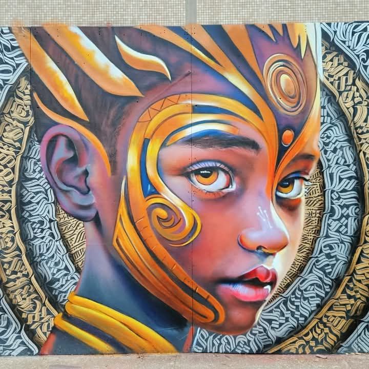 Vibrant street art mural of a face with colorful swirling patterns and ornate frame