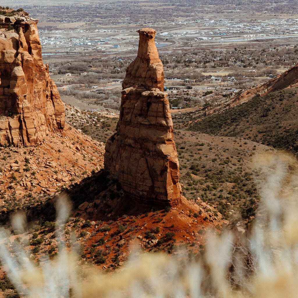 Independence Monument, a towering red rock formation in Colorado desert canyon with road below