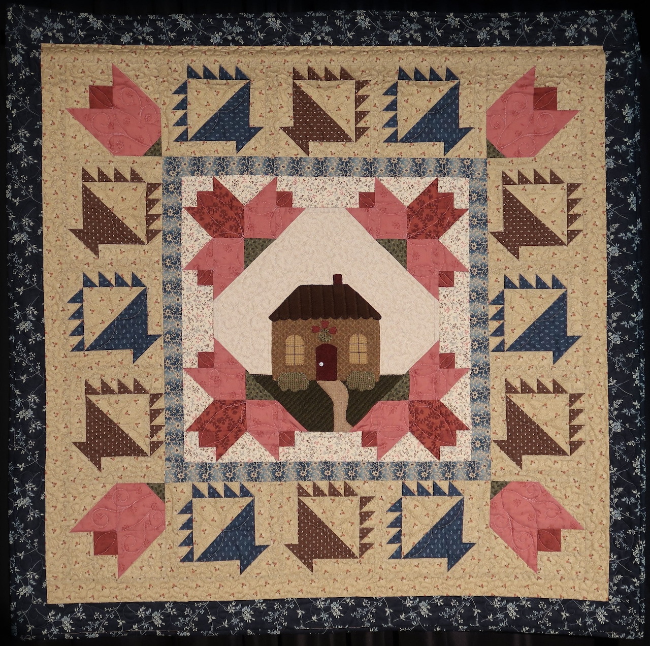 Quilt with cottage center, tulip blocks, flying geese border, and dark floral frame