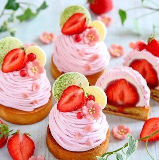 Pink swirled desserts with strawberries and white chocolate garnish on a marble surface