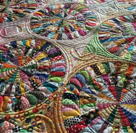 Close-up of a colorful patchwork quilt with circular stitching and many fabric patches