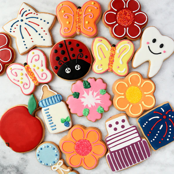 Assortment of decorated sugar cookies in butterfly, flower, ladybug, and other shapes with colorful royal icing