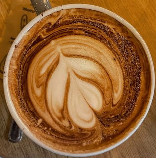 Top view of latte art coffee in a white cup on a wooden table