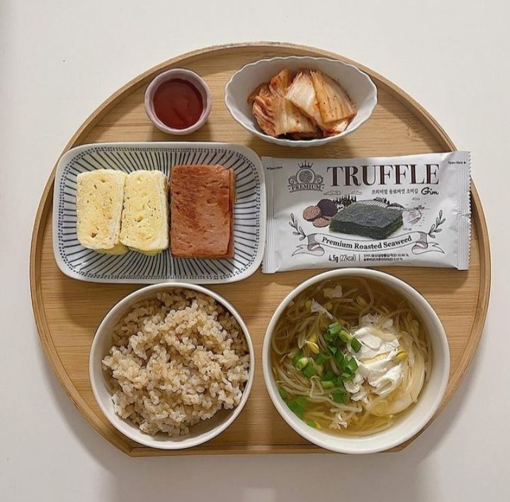 Overhead view of Japanese lunch set with rice, soup, tofu, and bread on wooden tray