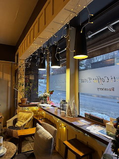 Warm cafe interior with wooden bar seating by large windows overlooking street