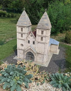 Miniature model of Ják Abbey Romanesque church with two towers in an outdoor park setting