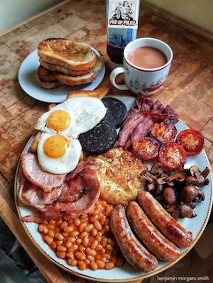 Large breakfast platter with eggs, bacon, sausages, beans, mushrooms, tomatoes, toast, coffee and orange juice