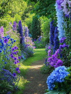 Garden path bordered by tall purple delphiniums, blue hydrangeas, and lush green hedges