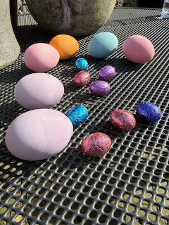 Pastel and metallic Easter eggs on a black metal mesh table outdoors