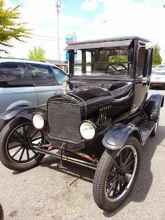 Shiny black Ford Model T vintage car parked in a parking lot on a cloudy day