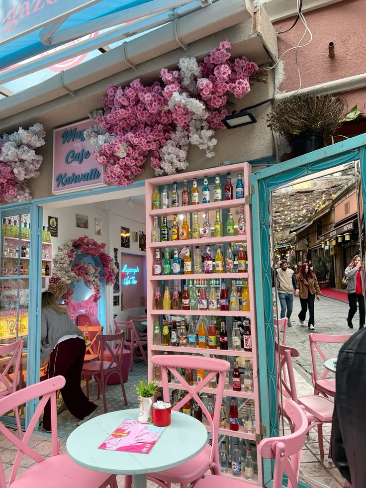 Pink café exterior with cherry blossom decorations and colorful drink bottles on shelves