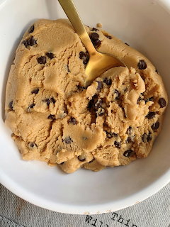 White bowl of chocolate chip cookie dough with a gold spoon viewed from above